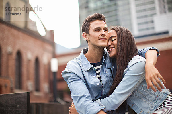 Junges Paar umarmt sich in der Stadt und lächelt