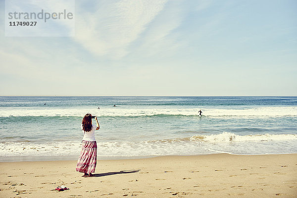 Rückansicht einer Frau am Strand beim Fotografieren des Ozeans  Venice Beach  Los Angeles  Kalifornien