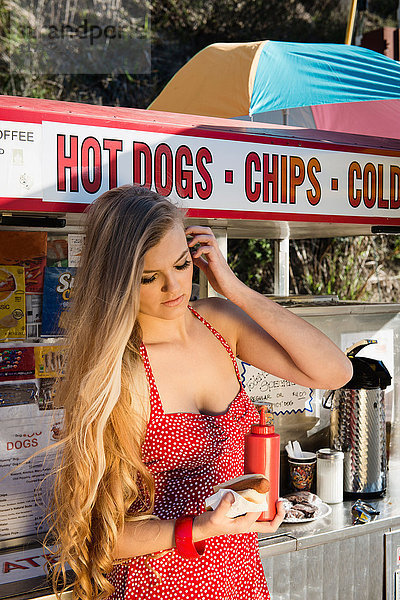 Junge Frau hält Essen am Hotdog-Stand