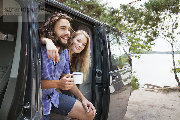 Junges Paar entspannt sich im Lieferwagen am See