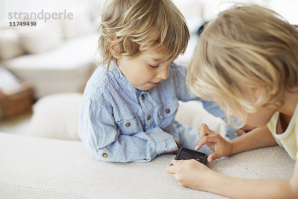 Zwei junge Brüder schauen auf Smartphone  berühren den Bildschirm