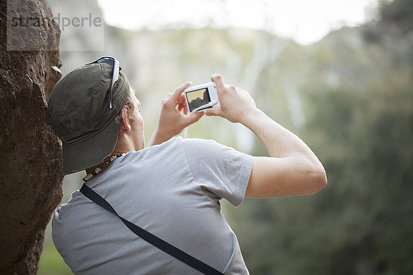 Junger Mann neben dem Rock fotografiert mit Digitalkamera