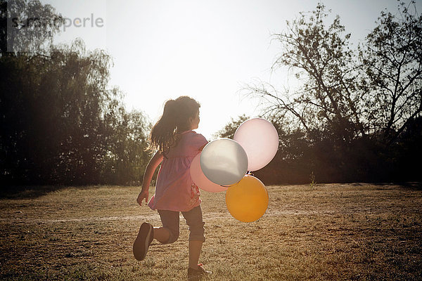 Mädchen läuft mit Luftballons