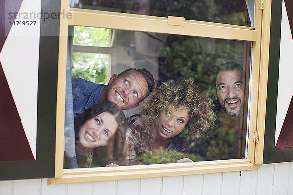 Vier erwachsene Freunde posieren beim Blick durch das Kabinenfenster