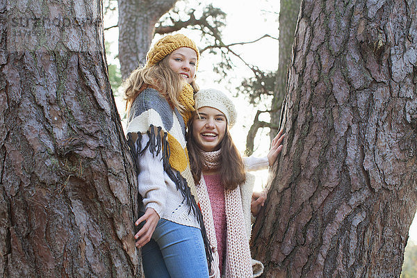 Porträt von Mädchen im Teenager-Alter  die in einem Baum stehen und lächelnd in die Kamera schauen