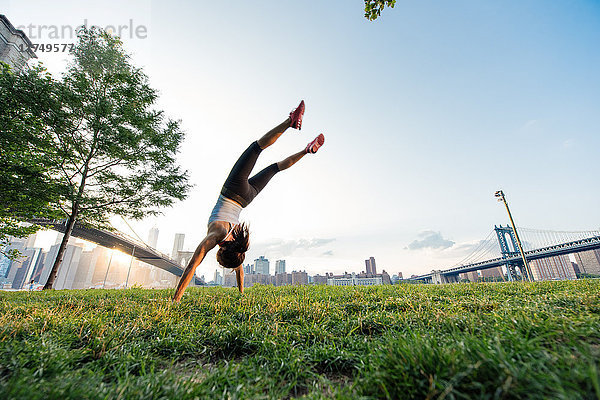 Junge Frau macht Handstand im Park  New York  USA