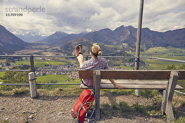 Reife Frau sitzt auf Bank und schaut auf die Berge  Garmisch-Partenkirchen  Bayern  Deutschland