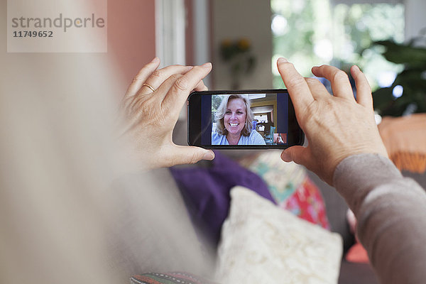 Ältere Frau  die ein Smartphone in der Hand hält  bei einem Videogespräch mit einem Freund