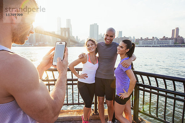 Laufende erwachsene Freunde posieren für Smartphone-Foto am Flussufer  New York  USA