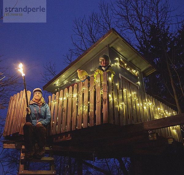 Mutter und Söhne auf einem Baumhaus aus Holz