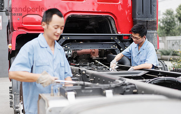 Zwei männliche Fabrikarbeiter arbeiten auf einem Lastwagen in einer Kranfabrik  China