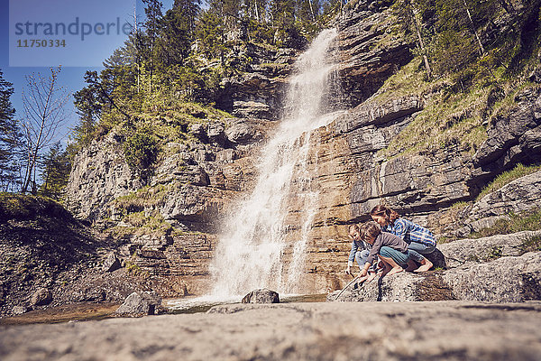Mutter und zwei Kinder erkunden neben dem Wasserfall