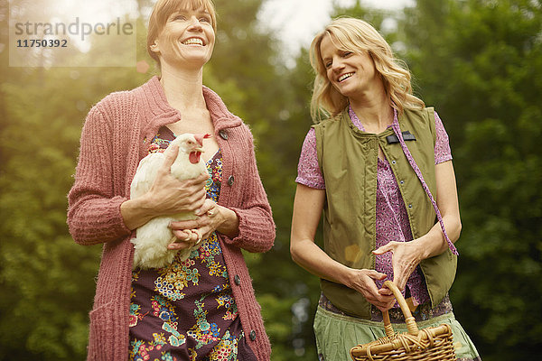 Zwei Frauen auf dem Feld tragen Henne und Korb