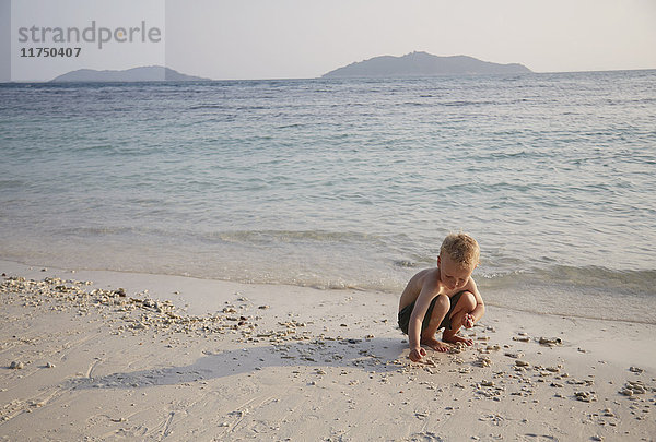 Junge spielt im Sand am Strand  Rawa Island Malaysia