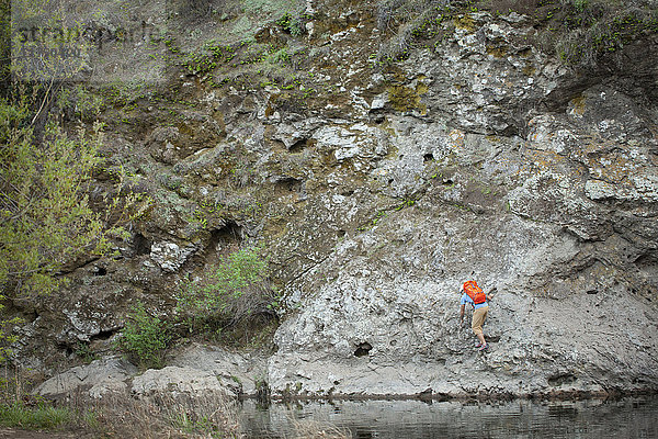 Junger Mann klettert am Felsen am Seeufer  Malibu Creek State Park  Kalifornien  USA