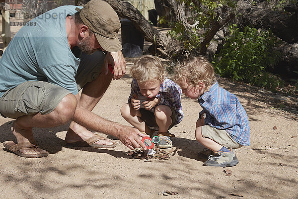Vater und Söhne versuchen  mit Lupe und Sonne ein Lagerfeuer zu entfachen  Purros  Kaokoland  Namibia
