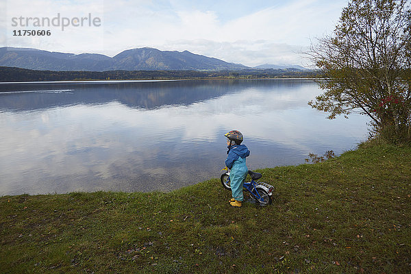 Junge steht mit Fahrrad am See