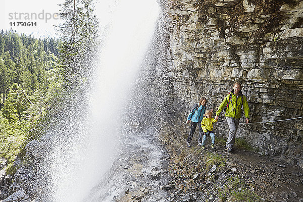 Junge Familie  zu Fuss unter einem Wasserfall