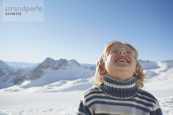 Porträt eines Jungen in verschneiter Landschaft  der aufschaut und lächelt