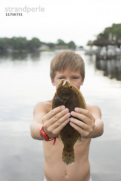 Porträt eines Jungen  der eine Flunder hochhält  Shalimar  Florida  USA