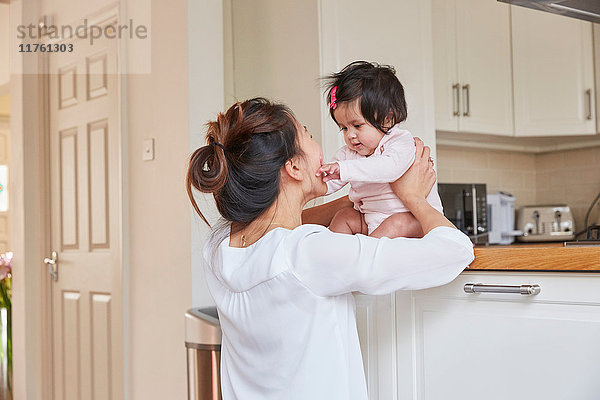 Frau hält Baby-Tochter auf Küchentheke