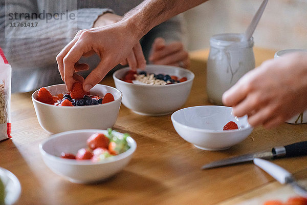 Hände eines jungen Paares bei der Zubereitung eines Obstfrühstücks an der Küchentheke