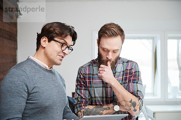 Männliche Designer schauen sich digitales Tablett im Design-Studio an