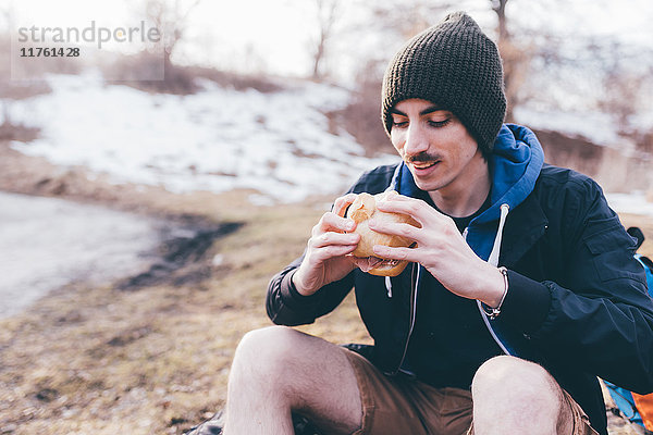 Junger männlicher Wanderer am Strassenrand beim Essen eines Sandwiches  Monte San Primo  Italien