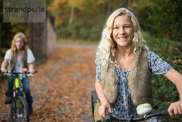 Porträt von zwei Schwestern beim Radfahren im Herbstpark