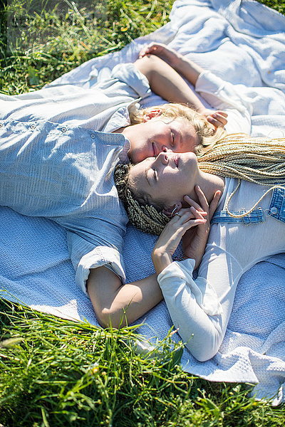 Draufsicht auf ein romantisches junges Paar  das auf einer Picknickdecke im Gras liegt  Mallorca  Spanien