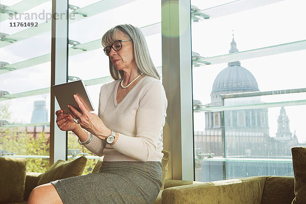 Geschäftsfrau benutzt digitales Tablet auf Bürosofa. London  Vereinigtes Königreich