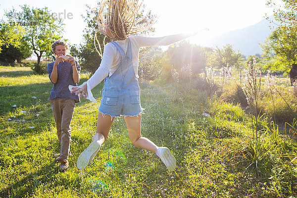 Lustige junge Frau  die im Feld springt und von ihrem Freund fotografiert wird  Mallorca  Spanien