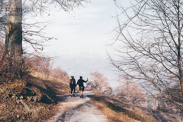 Rückansicht eines Wanderpaares beim Wandern entlang einer Landstraße  Monte San Primo  Italien