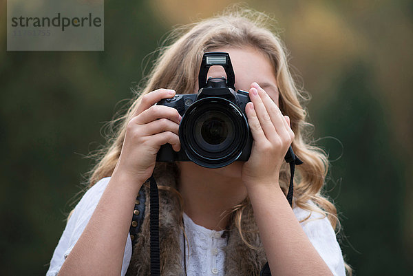 Porträt eines Mädchens  das mit einer digitalen Spiegelreflexkamera fotografiert