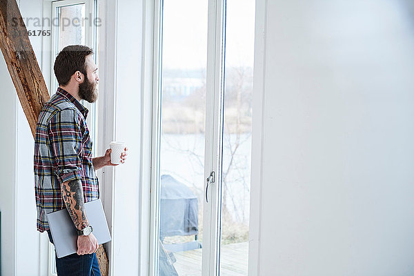 Junger männlicher Designer schaut durch ein Fenster im Design-Studio