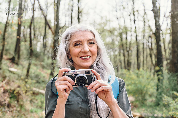 Reife Frau mit langen grauen Haaren beim Fotografieren im Wald  Scandicci  Toskana  Italien