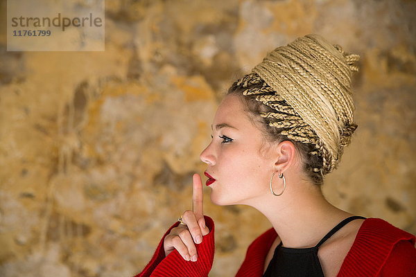 Profil einer jungen Frau mit Dreadlocks  Finger an Mund