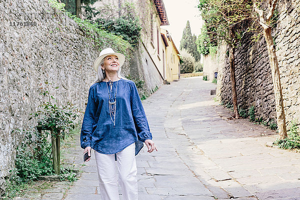 Stilvolle  reife Frau schlendert auf gepflasterter Straße  Fiesole  Toskana  Italien