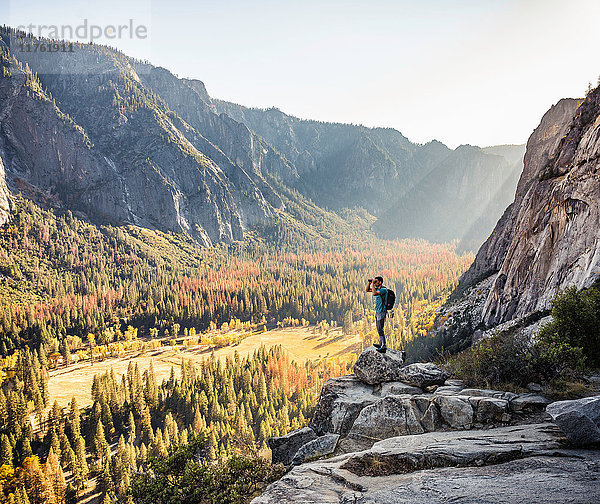 Mann auf felsiger Kante  der durch ein Fernglas hinaussieht  Yosemite National Park  Kalifornien  USA