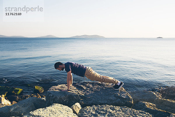 Mann macht Push-Ups auf Felsen auf dem Meer  Istanbul  Türkei