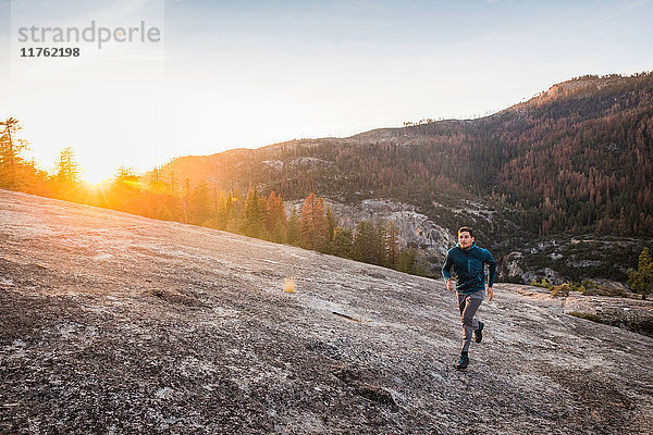 Mann läuft bei Sonnenuntergang auf Felsoberfläche  Yosemite National Park  Kalifornien  USA