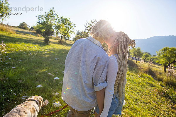 Romantisches junges Paar beim Hundespaziergang in sonniger ländlicher Umgebung  Mallorca  Spanien
