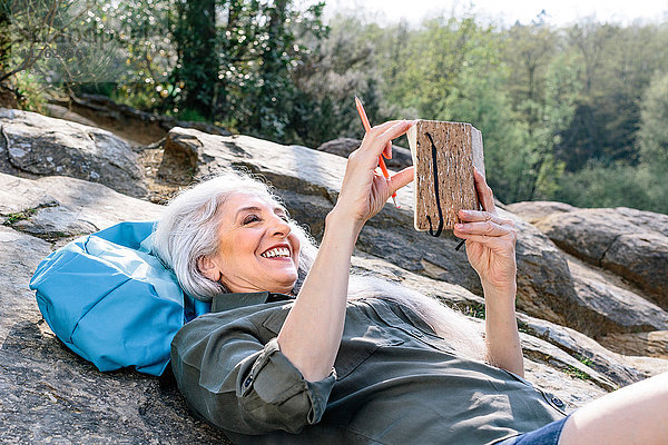 Ältere Backpackerin auf einem Felsen im Wald liegend  Scandicci  Toskana  Italien