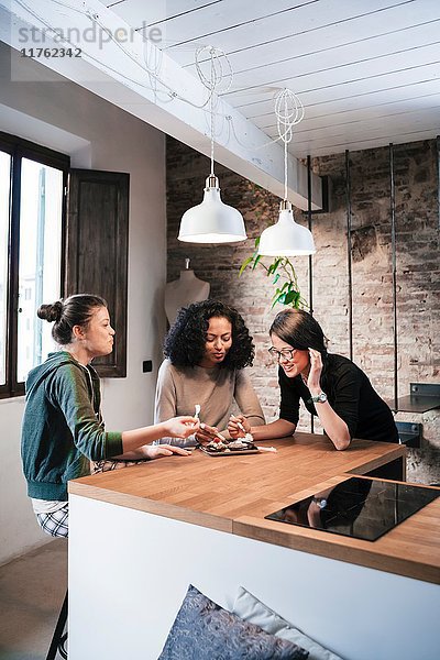 Freunde mit Muffins an der Küchentheke sitzend