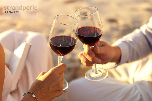 Ehepaar trinkt Rotwein am Strand