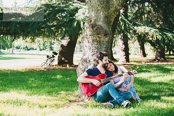 Paar sitzt im Park und spielt Gitarre  Arezzo  Toskana  Italien
