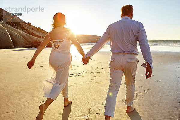Ein erwachsenes Paar geht am Strand spazieren  Hand in Hand  Rückansicht  Kapstadt  Südafrika