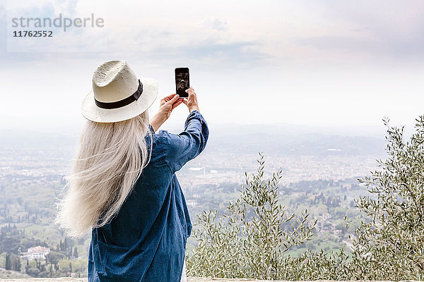 Rückansicht einer reifen Frau mit langen grauen Haaren beim Fotografieren  Fiesole  Toskana  Italien