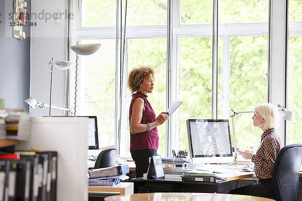 Zwei Innenarchitektinnen besprechen Stoffmuster am Büroschreibtisch