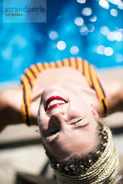 Junge Frau mit Dreadlocks  neben dem Schwimmbad  erhöhte Ansicht